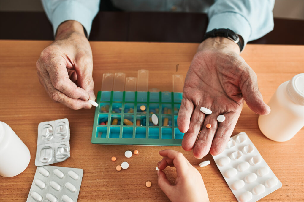 senior man organizing his medication into pill dispenser. senior man taking pills from box. healthcare and old age concept with medicines. medicaments on table